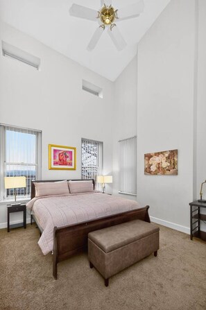 A bedroom with a bed, a bench, a ceiling fan, and artwork on the walls. - Renovated FL3| Near UC+TQL Stadium | Free Parking (Cincinnati)
