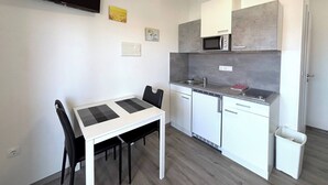 A compact kitchen with a microwave, sink, and a small dining area with a table and chairs. - Sea View Apartment Marijana (Preko)