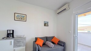 A modern living room with a grey sofa, orange cushions, a coffee maker, and a small cabinet. - Sea View Apartment Marijana (Preko)
