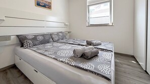 A modern bedroom with a bed, pillows, a window, and a painting on the wall. - Sea View Apartment Marijana (Preko)
