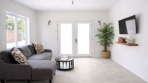 A modern living room with a grey sofa, a round coffee table, and a potted plant.