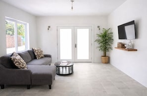 Una sala moderna con un sofá gris, una mesa de centro redonda y una planta en maceta.