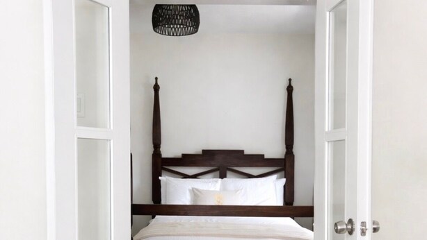 A bedroom with a bed, white walls, and a tiled floor.