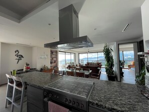 A modern kitchen with a central island, built-in oven, and a large window overlooking a scenic view. - Exclusive, unparalleled view, La Isla Residences Acapulco (Acapulco de Juárez)