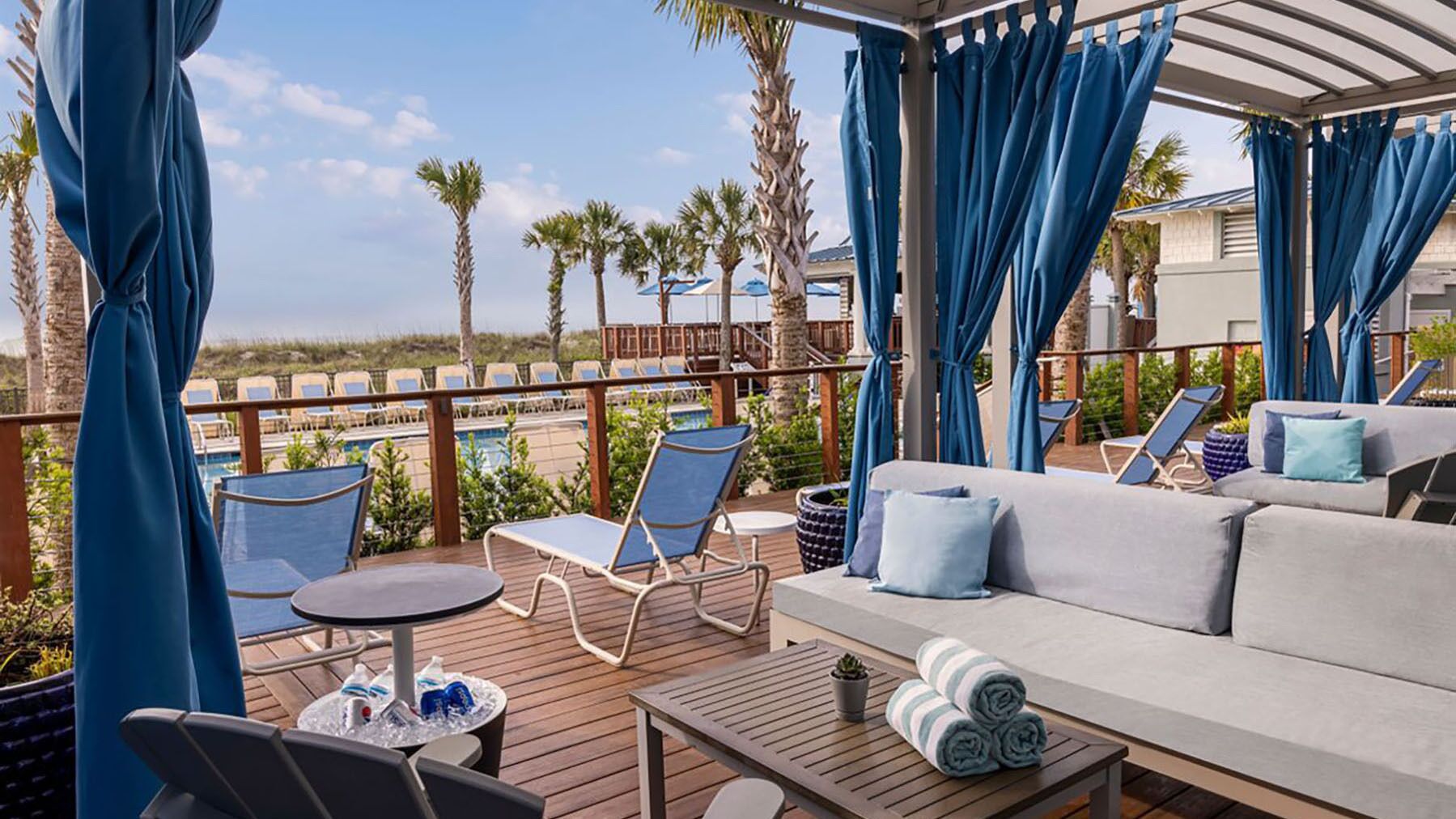 A covered outdoor area with a pool, lounge chairs, and a sofa.