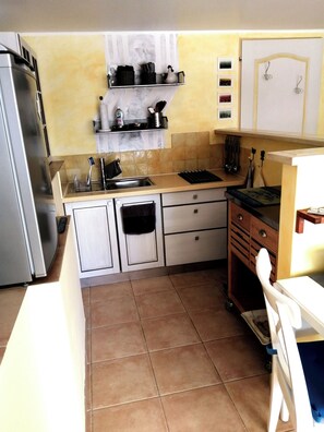 Eine kleine Küche mit Kühlschrank, Spüle und Holzschränken.