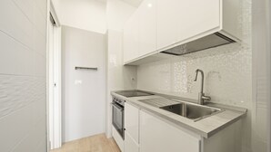 A modern kitchen with white cabinetry, a double sink, and a built-in oven. - Alpha Domus 15 (Naples)