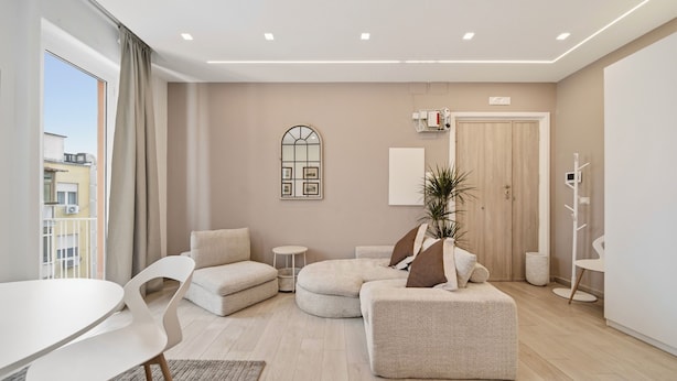 A modern living room with a round coffee table, a sofa, a small side table, and a potted plant. - Alpha Domus 15 (Naples)