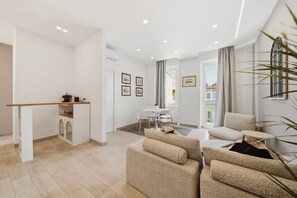 Ein modernes Wohnzimmer mit einer Sofagarnitur, einem Essbereich mit Tisch und Stühlen sowie einer Küchenzeile mit Arbeitsplatte und Schränken.
