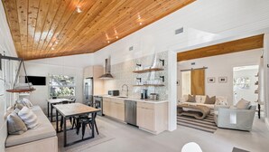 A modern kitchen with wooden beams, a dining area with a table and chairs, and a living space with a sofa and a coffee table. - Steps to Beach Access w/ Screened Porch (Santa Rosa Beach)