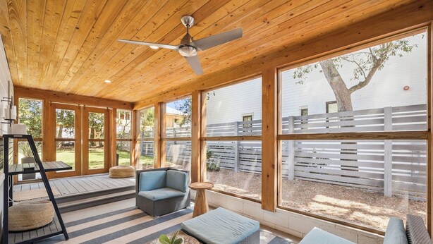 A covered patio with a ceiling fan, wicker furniture, and large windows offering a view of a fenced backyard. - Steps to Beach Access w/ Screened Porch (Santa Rosa Beach)