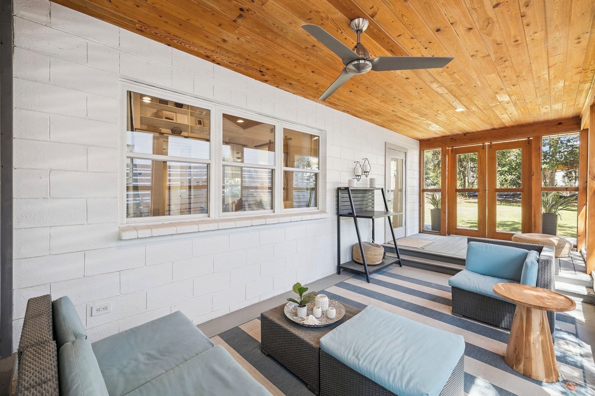 A covered patio area with a ceiling fan, a seating area with cushions, and a view of the outdoors.