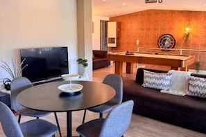 A modern living room with a pool table, a flat-screen TV, and a comfortable couch.