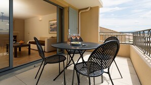Ein Balkon mit rundem Tisch und vier Stühlen, einer Wasserflasche und einem Weinglas.