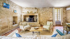 Una habitación con paredes de piedra, una chimenea, dos sillones, un sofá y una mesa de comedor.