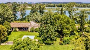 Una casa con piscina, rodeada de vegetación exuberante y un lago.