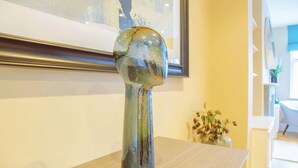 A sculpture on a table with a framed picture and a vase with flowers in the background. - Elegant 4-bed Apartment in Pimlico Sleep 7 (London)