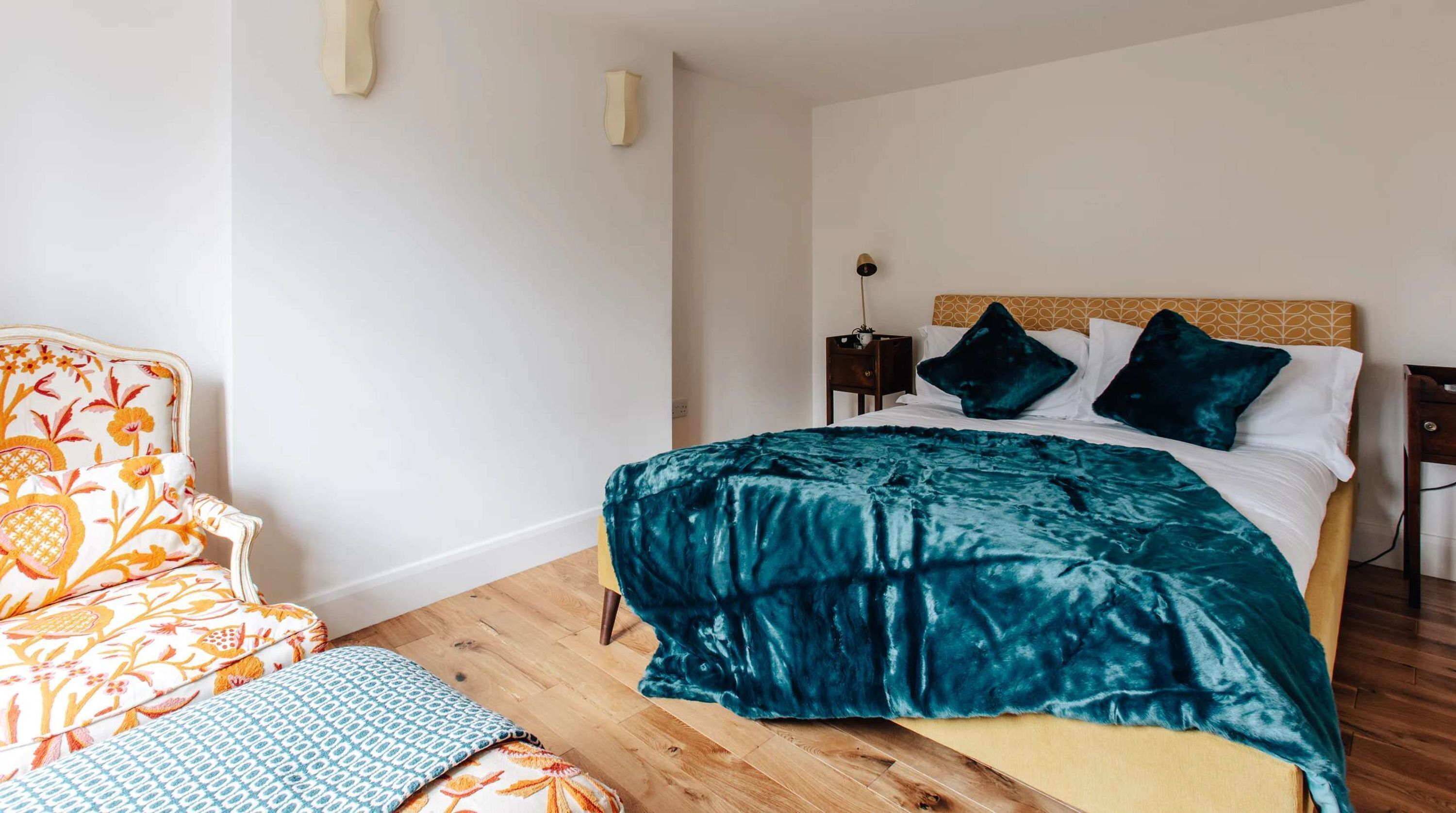 A bedroom with a bed, a chair, and a nightstand.
