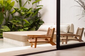A room with a bed, two wicker chairs, a small table, and a large window. - Designer Pool Luxury Escape Villa in Canggu (Jimbaran)