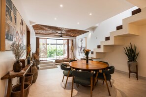 A modern dining area with a round table, chairs, and a potted plant. - Designer Pool Luxury Escape Villa in Canggu (Jimbaran)