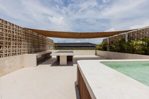 A rooftop pool area with a table and benches, surrounded by a lattice fence and greenery. - Designer Pool Luxury Escape Villa in Canggu (Jimbaran)