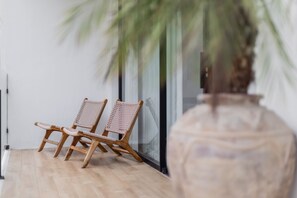 A room with two wicker chairs, a large vase, and a glass door. - A Canggu Sojourn Villa (Cemagi)