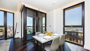Un comedor moderno con una mesa dispuesta para cuatro personas, ventanas amplias y vistas a la ciudad.