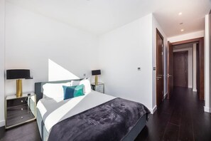 A modern bedroom with a bed, bedside tables, and a wardrobe. - Stylish 2-bed Apartment in Battersea (London)