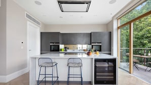 Una cocina moderna con una isla central, taburetes de bar y vistas al exterior.