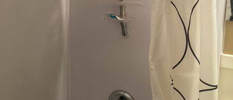 A shower with a handheld showerhead, a control panel, and a curtain.