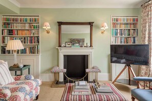 A living room with a fireplace, bookshelves, a television, and patterned furniture. - Gorgeous 3 Bedroom Flat - Pimlico (London)