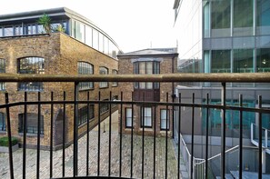 A courtyard with a brick building, a modern glass structure, and a metal railing. - Elegant 2 Bedroom Flat - King's Cross (London)