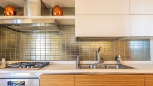 A modern kitchen with a stainless steel stove, a sink, and wooden cabinets.