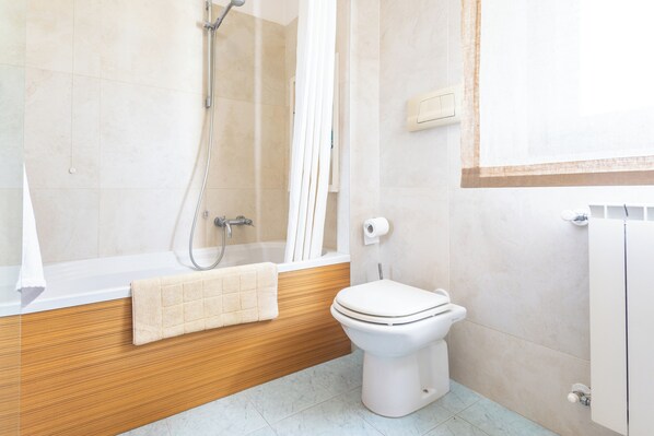 A bathroom with a bathtub, a toilet, and a shower. - Palazzo Ninfea (Sambuceto)