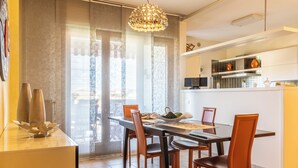 A modern dining area with a glass table, brown chairs, and a pendant light.