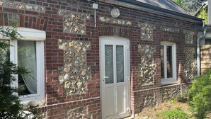 A brick building with a stone facade, a white door, and a window with a curtain.
