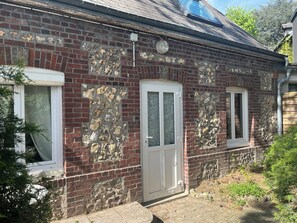 A brick building with a stone facade, a white door, and a window with a curtain. - Charming little house with private terrace in the center of town. (Rouen)
