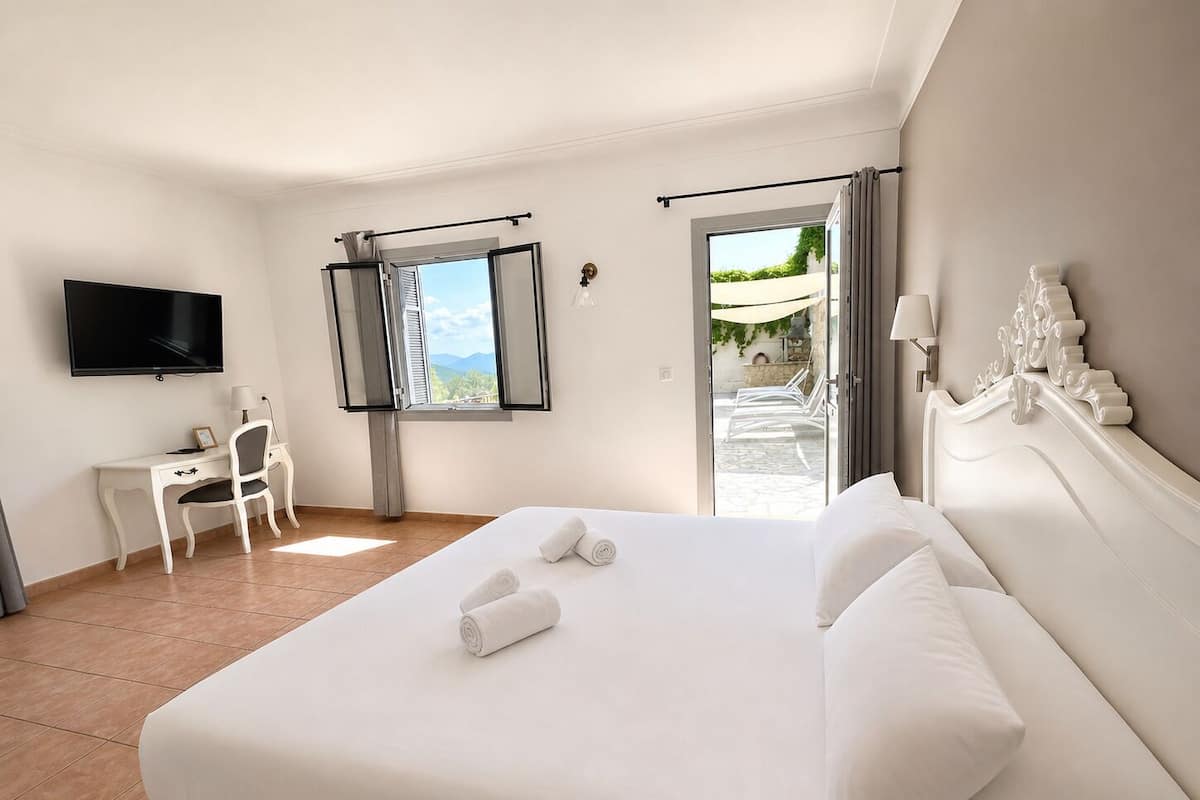 Habitación de hotel con cama, escritorio, silla, televisión y ventana con vistas.