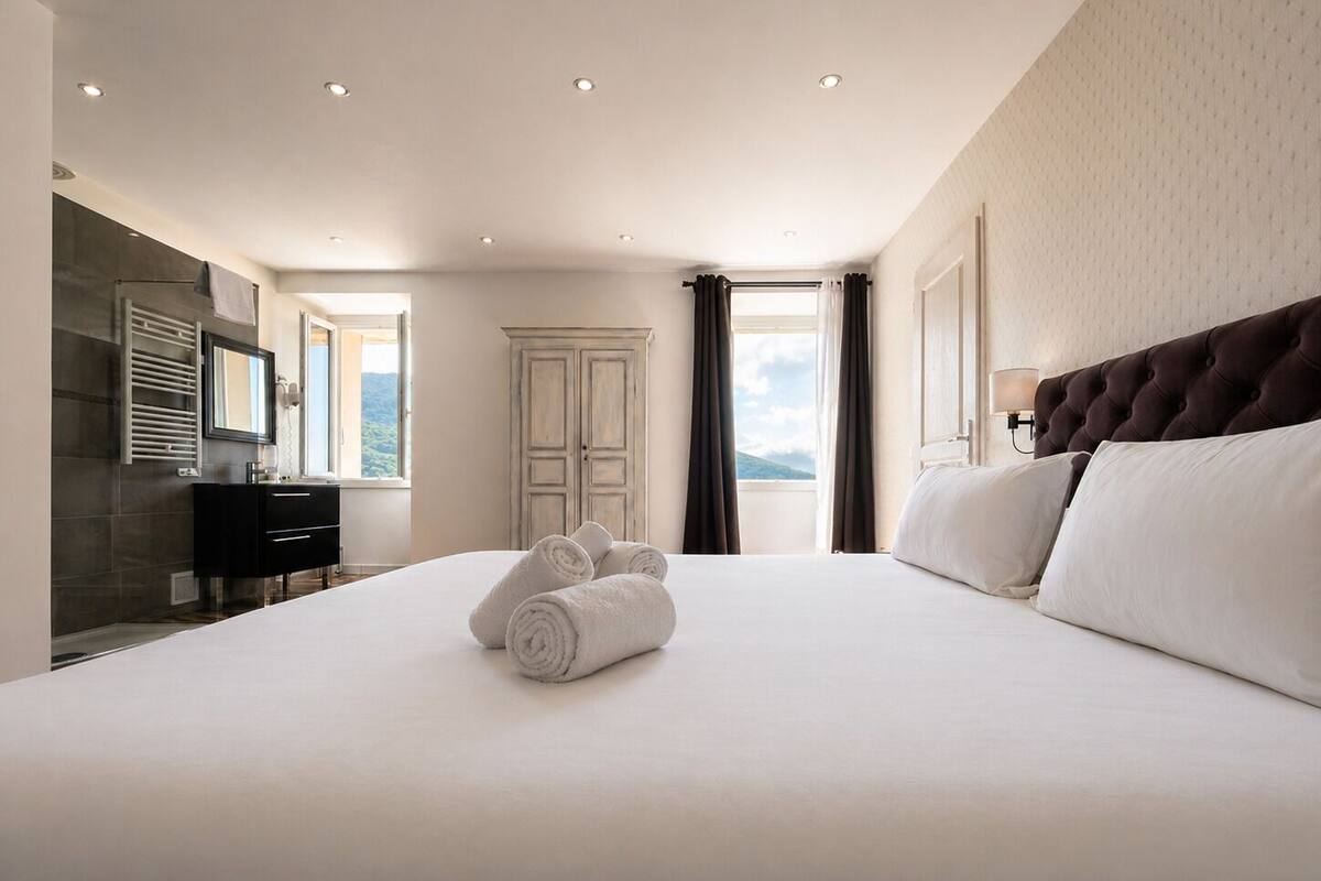 Habitación de hotel con una cama grande, un armario, un espejo y vistas al exterior.