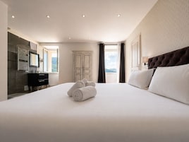 Habitación de hotel con una cama grande, un armario, un espejo y vistas al exterior.