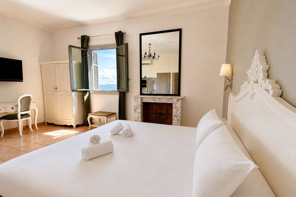 Habitación de hotel con cama, escritorio, silla, televisión, chimenea y ventana con cortinas.