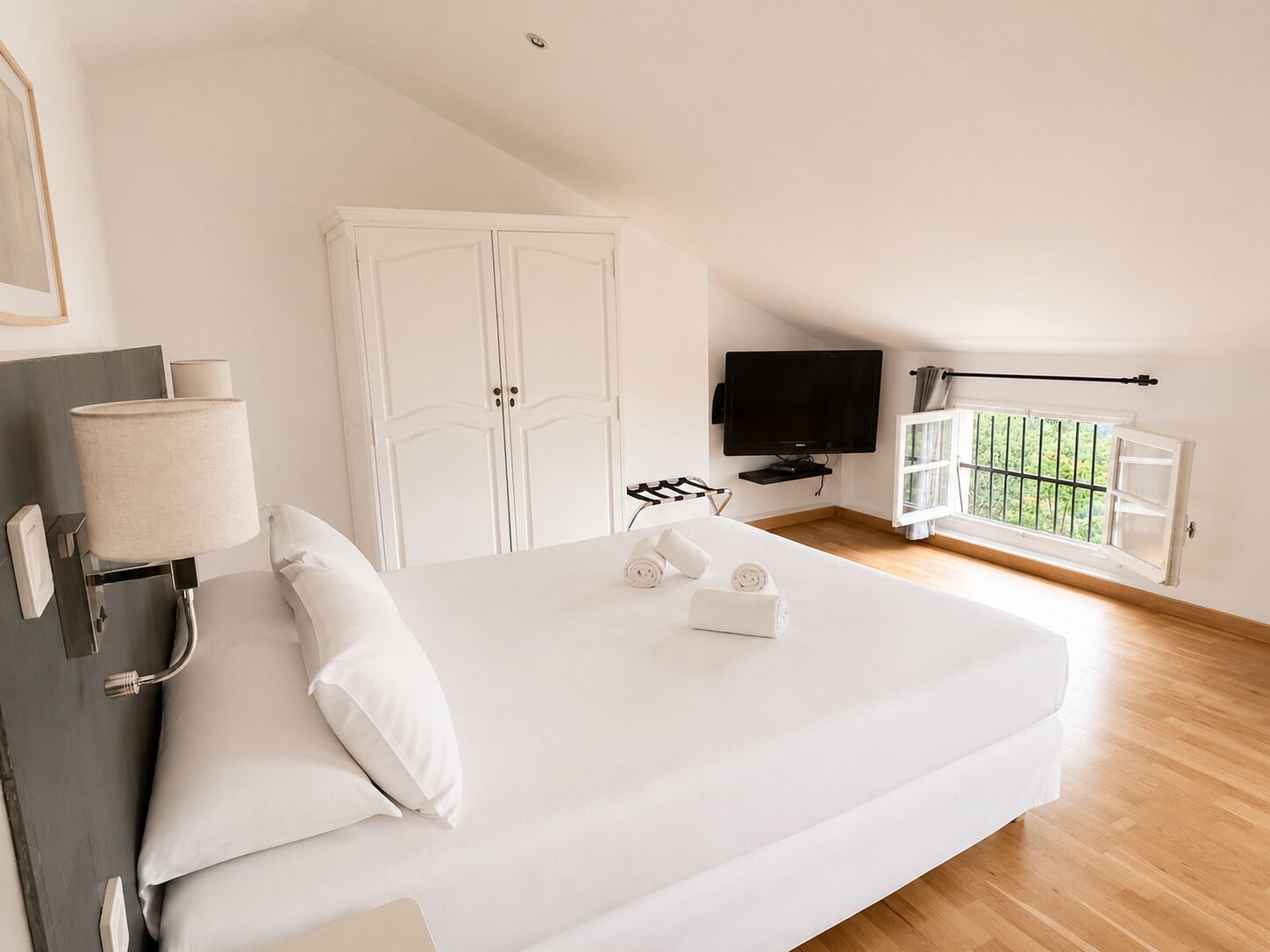 Quarto com cama, televisão, guarda-roupa e janela.