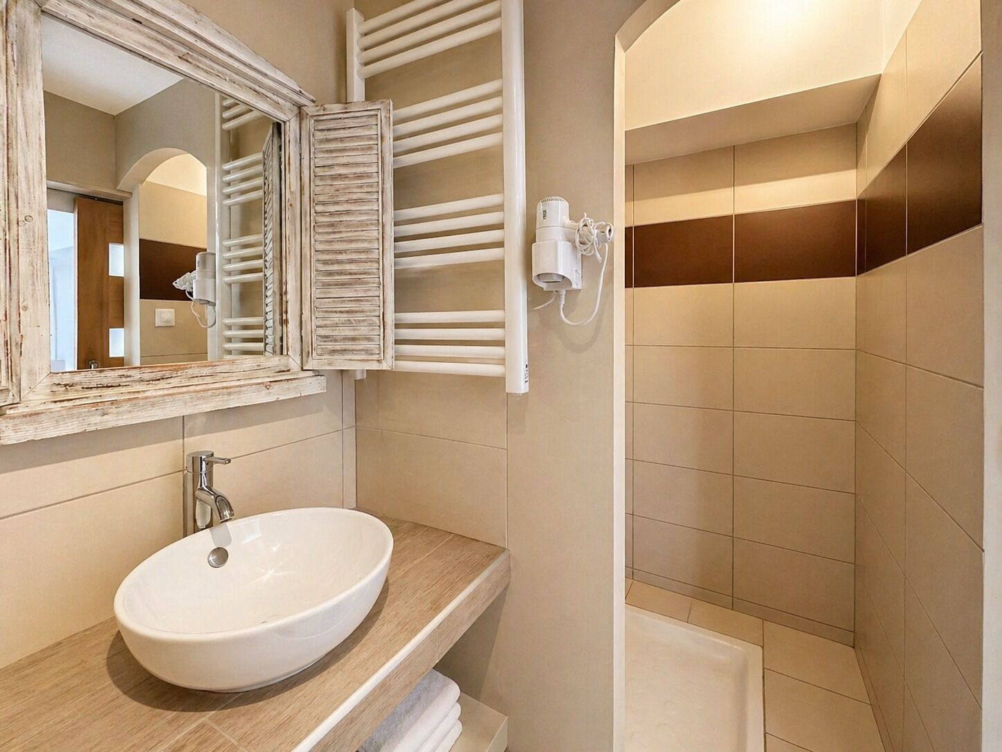 A bathroom with a white sink, a mirror with a rustic frame, a towel rack, and a shower area.
