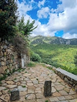 Un sendero de piedra que conduce a un paisaje montañoso, con un muro de piedra a un lado.