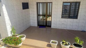 A tiled courtyard with a door, potted plants, and a window.