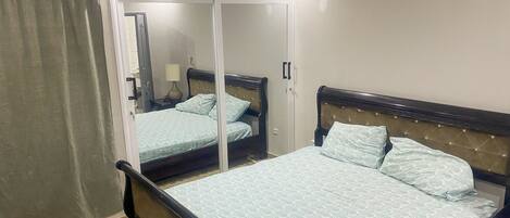 Une chambre à coucher comprenant un lit, une armoire, un miroir et un ventilateur de plafond.