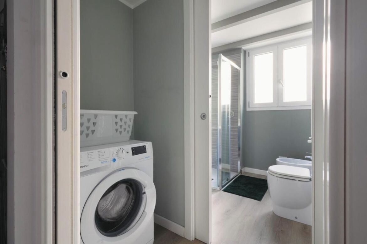 Ein Waschbereich mit Waschmaschine, Toilette und Duschbereich.