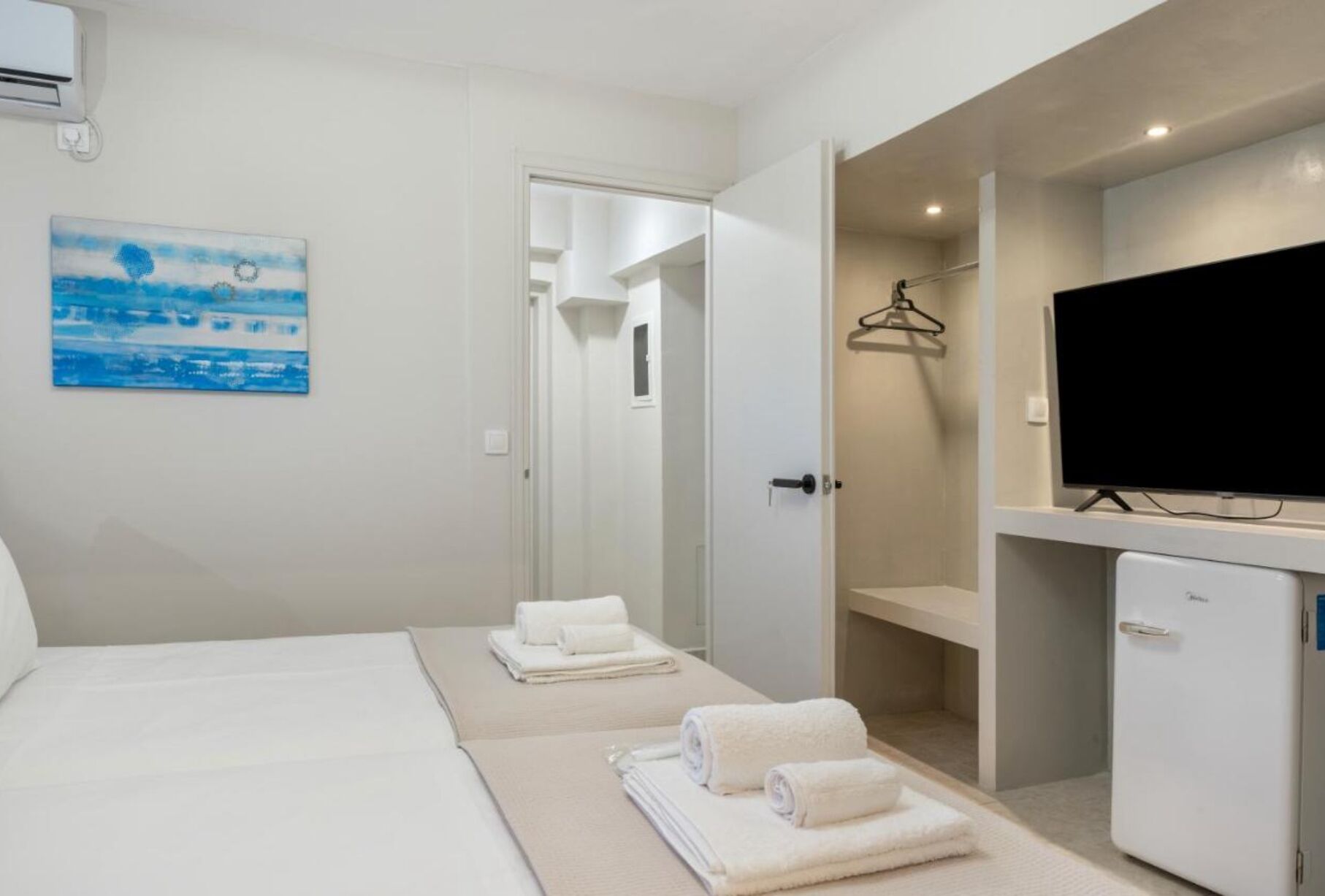 Ein Hotelzimmer mit Bett, Fernseher, Schreibtisch und angrenzendem Badezimmer.