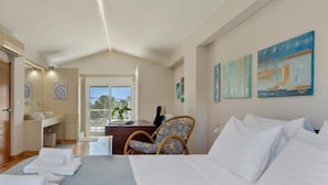 Een hotelkamer met een bed, een bureau, een stoel, uitzicht op een balkon en kunst aan de muur.
