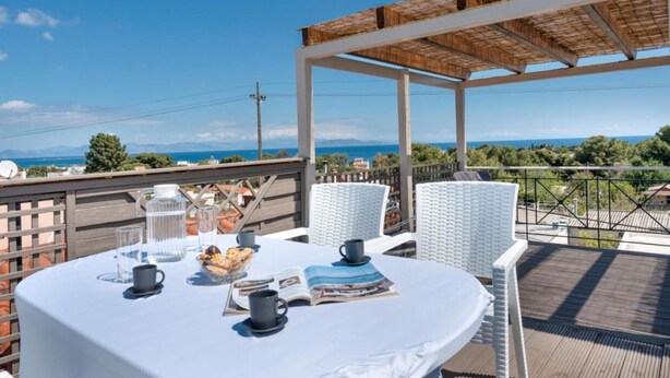 Een overdekt terras met een tafel gedekt voor twee personen, met uitzicht op een schilderachtig panorama.